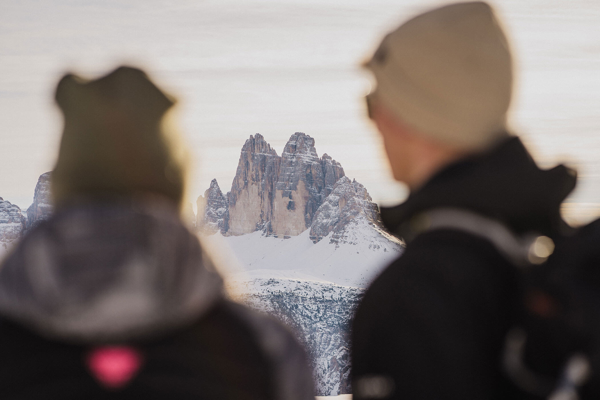 A couple looking at the snow-covered Three Peaks in winter • SkyView Chalets Toblacher See