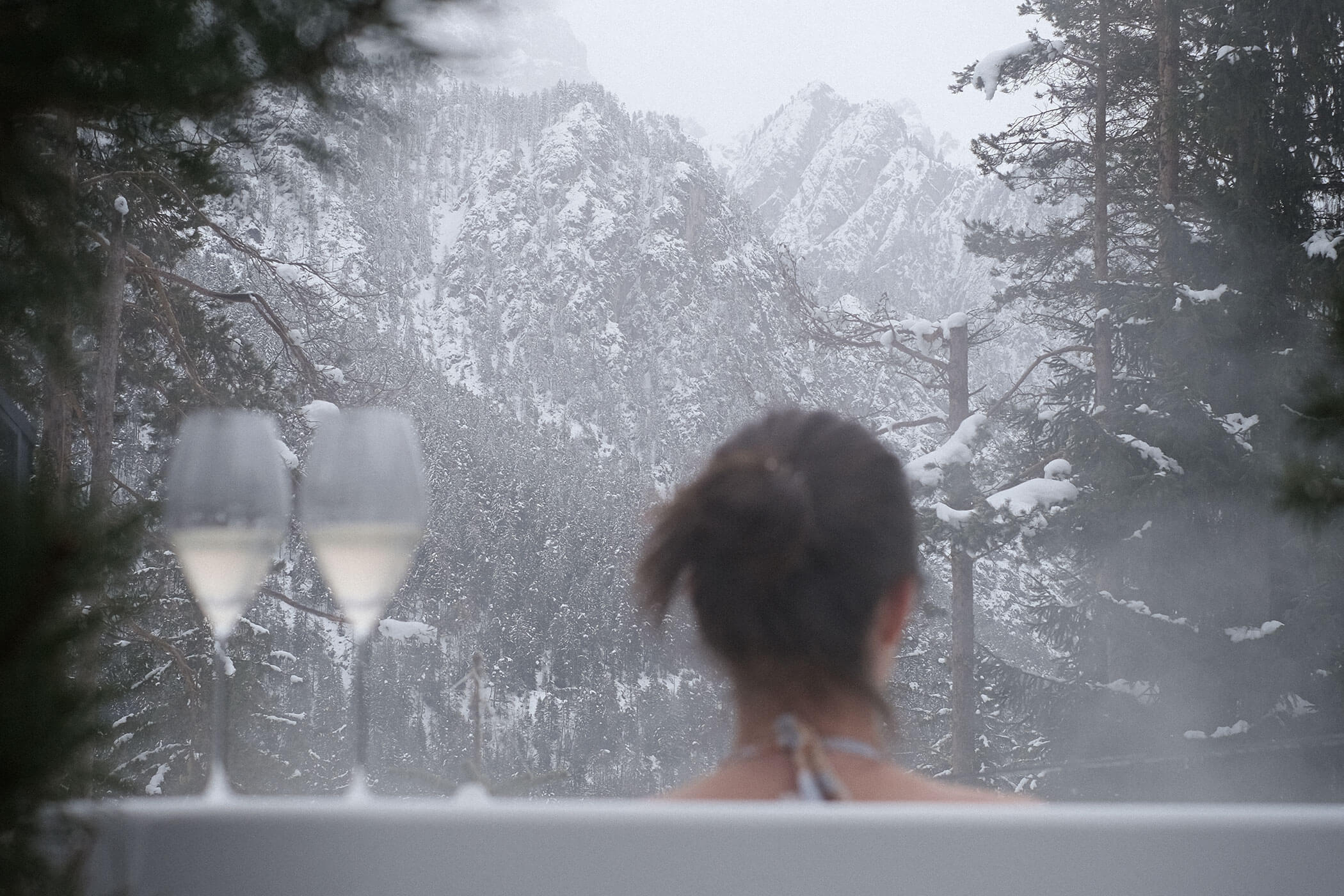 Woman in the water looking at snow-covered mountains • SkyView Chalets Toblacher See
