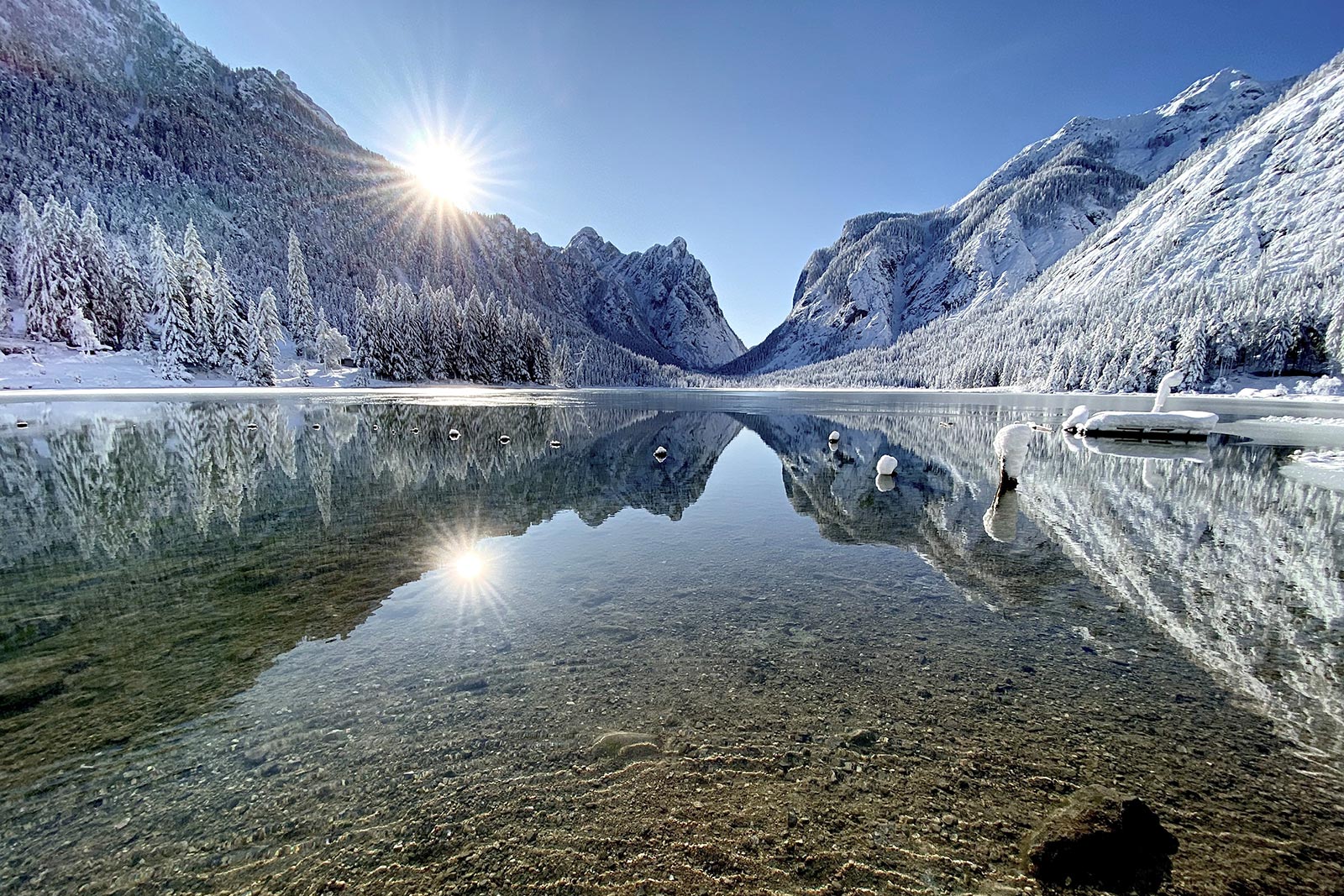White mountain landscape behind Lake Dobbiaco • SkyView Chalets Toblacher See
