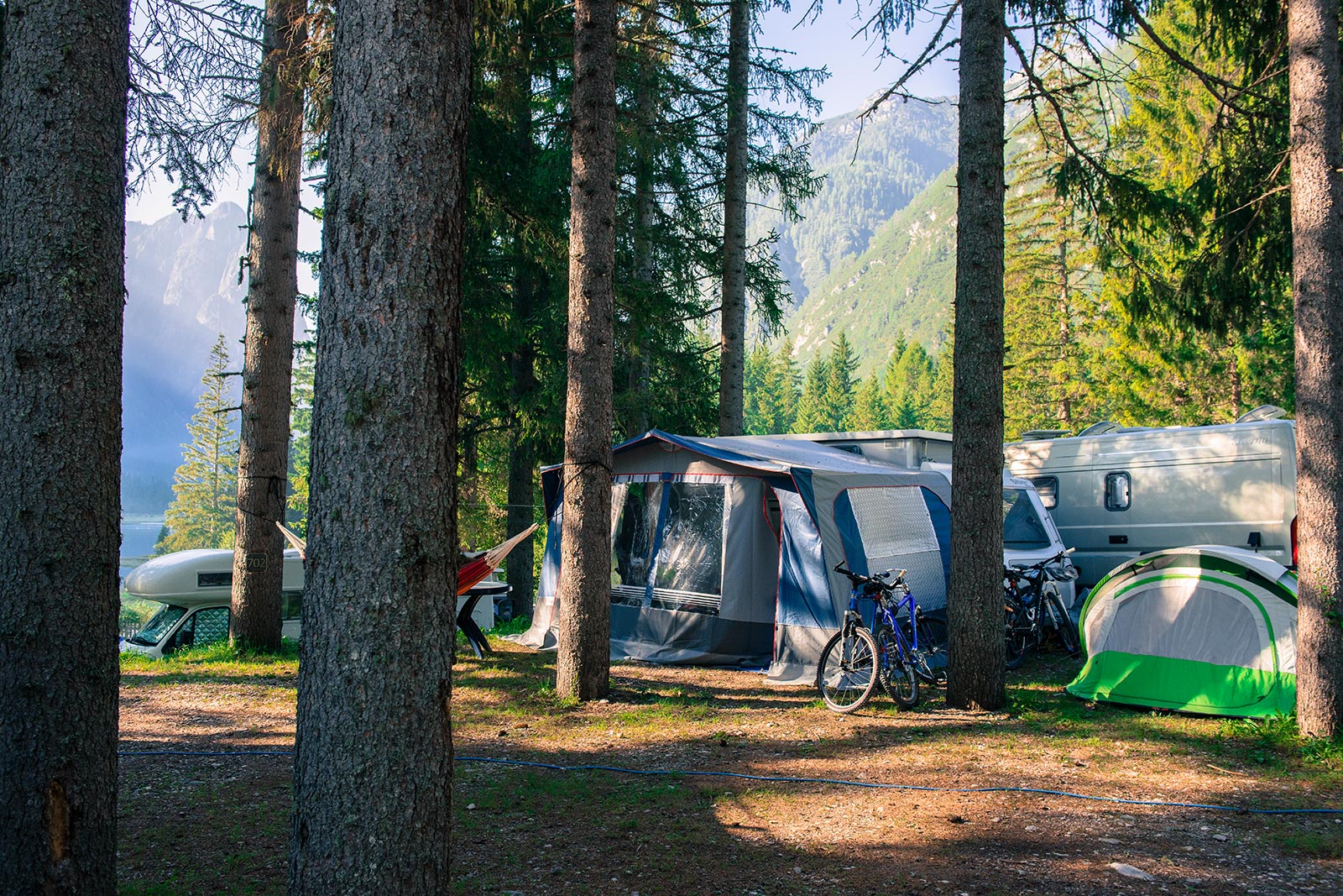 Zeltplatz mit Camper im Wald zwischen den Bäumen - Camping Toblacher See