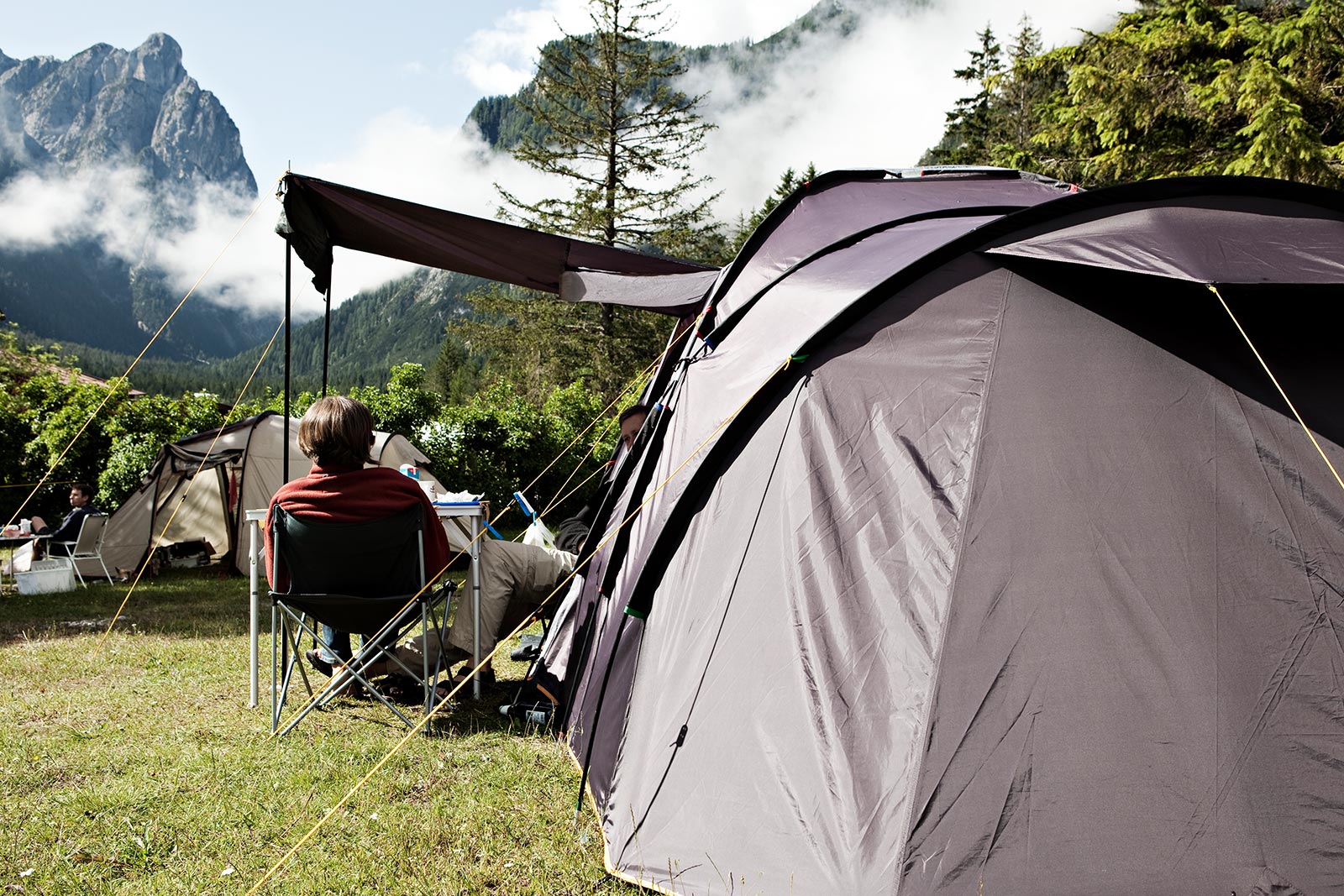 Detailaufnahme - zwei Personen auf Campingstühlen vor einem Zelt - Camping Toblacher See